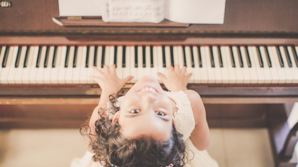 A happy little girl learning About Suzuki Piano lessons. 
